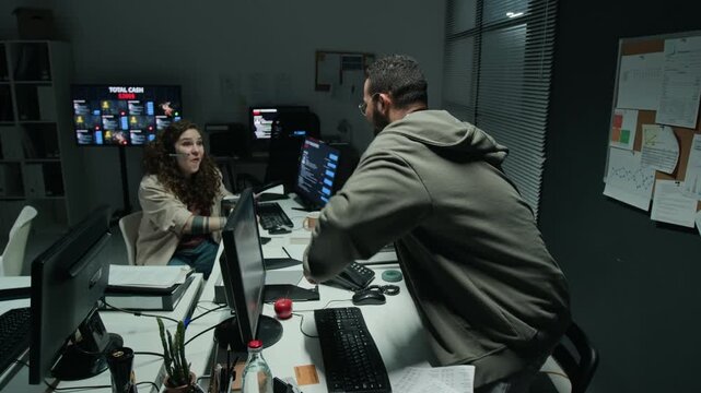 Young biracial man and Caucasian woman celebrating success and giving high five in scam call center office. Perfect for cybersecurity and scam awareness