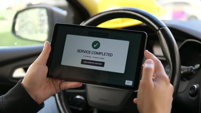 Driver checks a completed vehicle service on a tablet, highlighting digital maintenance records, preventive car care and connected automotive service management.