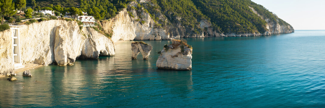 Baia delle Zagare empty beach sunrise Faraglioni sea stacks Gargano Puglia Italy drone panorama high resolution of iconic rock stacks and vertical cliffs over turquoise sea