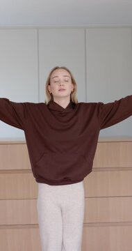 Vertical video: Woman breathing by dresser jar lifting arms from out to mudra to prayer to meditate