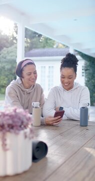 Vertical video: African American women friends reacting to red phone on porch table, laughing
