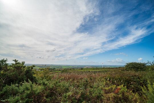 Cornish countryside landscape with rolling green fields and a distant wind turbine