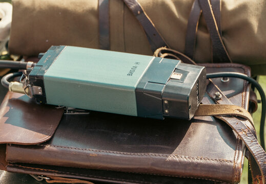 Minsk, Belarus - 08.13.2026: A vintage Soviet portable radio transceiver rests on a brown leather shoulder bag outdoors in natural daylight.
