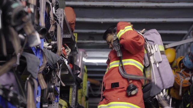 Asian firefighter taking air tank from shelf in equipment room