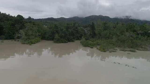 Turbid water runoff after heavy rain flowing into coastal mangrove forests, showing environmental sedimentation and climate impact.