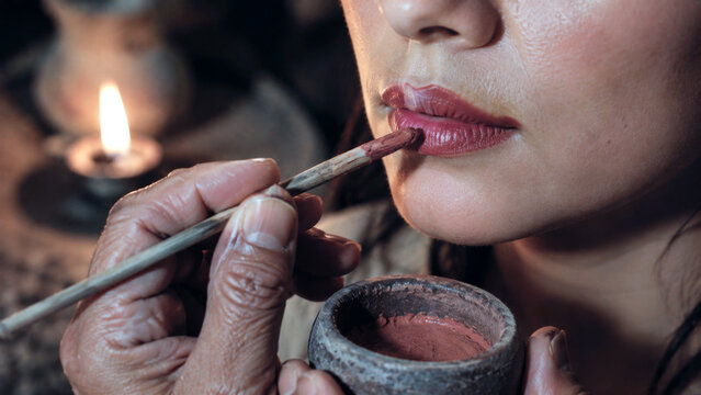 Traditional lip pigment applied with a brush using ancient inspired cosmetic methods in a historical beauty ritual
