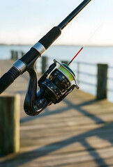 Fototapeta premium Leisure and recreation, fishing rod with spinning reel on a wooden pier at sunrise for outdoor hobby and travel lifestyle photography