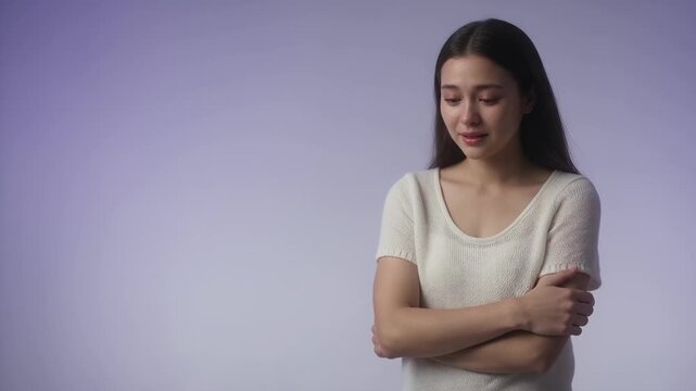 Emotions - Sad young asian woman crying and hugging herself with lonely and depressed expression in studio