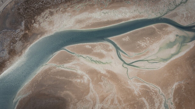 Aerial view of abstract patterns of blue water and brown sands at the coastline in Useless Loop, Western Australia, Australia.
