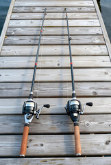 Fototapeta premium Leisure and recreation, two fishing rods on a wooden dock for outdoor hobby and travel lifestyle, summer vacation activity at the lake or river