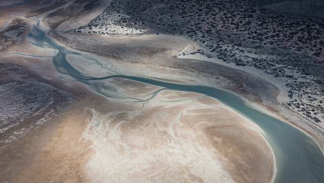 Aerial view of abstract patterns formed by turquoise blue water and brown sands along the coastline in Useless Loop, Western Australia, Australia.