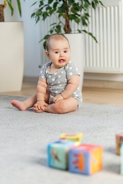 Baby girl sitting on rug playing with colorful blocks indoors