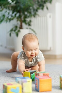 Baby crawling and reaching for colorful blocks indoors