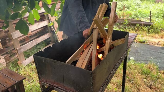 A man is lighting a fire in a barbecue grill outdoors. High quality 4k footage