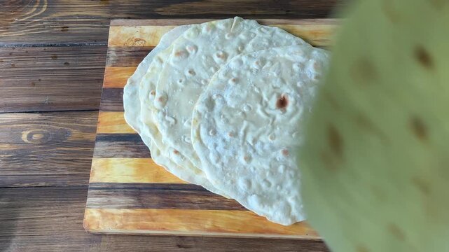 Top-down view of lavash flatbreads falling onto a wooden board. High quality 4k footage