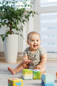Laughing baby sitting with colorful building blocks indoors