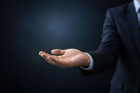 Open palm presentation gesture of businessman hand ready to receive or offer with negative space mockup for holographic overlay technology and business concept on dark studio background