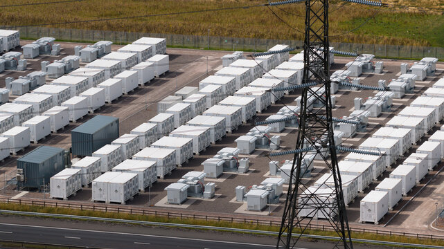 Aerial view of the Coalburn Battery Energy Storage System featuring rows of white energy storage containers and a transmission tower in a gravel facility Coalburn, Scotland, United Kingdom.