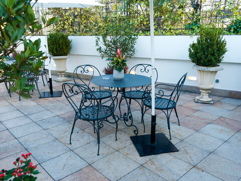 Terrasse am&eacute;nag&eacute;e avec tables, chaises en m&eacute;tal, parasols et plantes pour une r&eacute;ception &eacute;v&eacute;nementielle en ext&eacute;rieur