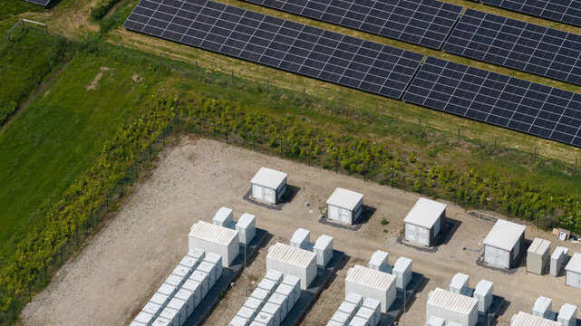 Aerial view of a solar farm with rows of photovoltaic panels and battery storage units in Wanneperveen, Overijssel, Netherlands.
