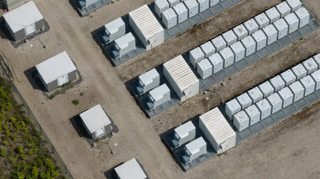 Aerial view of a battery energy storage system facility with rows of white battery containers and electrical equipment on a gravel site in Wanneperveen, Overijssel, Netherlands.