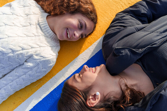 Two happy teenagers connecting, smiling and laughing together on a vibrant colorful ground