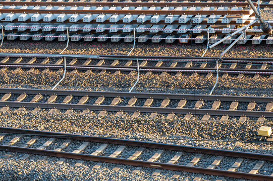 Concrete sleepers stacked along active railway construction lines. Sunlight highlights track repair and civil engineering materials for industrial infrastructure projects