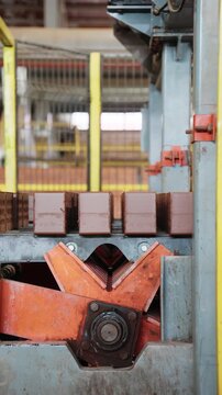 Red bricks moving along a conveyor line with drive sprockets at a brick factory