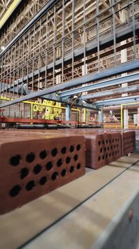 Red perforated bricks on a conveyor at an automated brick factory