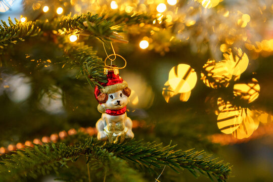 Close-up of Christmas ornament toys and balls hanging on a decorated tree with warm lights, festive tinsel and cozy holiday atmosphere at home.