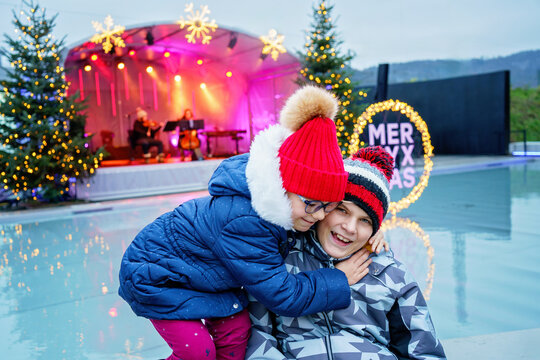 Two little smiling kids, boy and girl with christmas tree. Happy children in winter clothes on Christmas market with lights on background. Brother and sister together. Family, tradition, holiday