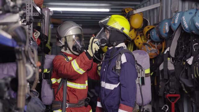 Firefighters checking safety breathing mask for buddy at station