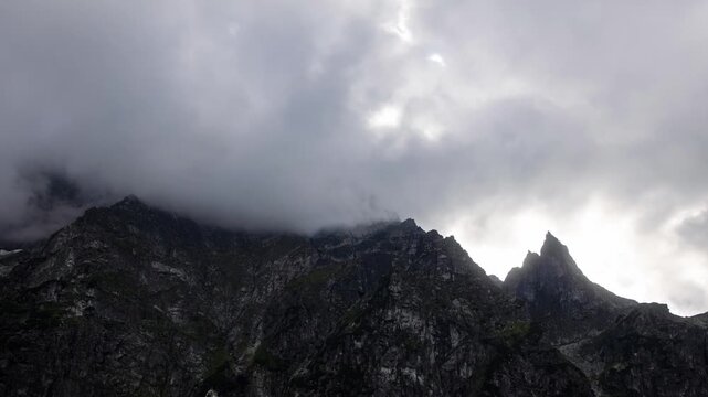 View of the rugged mountain peaks of Morskie Oko partially obscured by dramatic clouds in Tatra County, Lesser Poland Voivode, Poland.