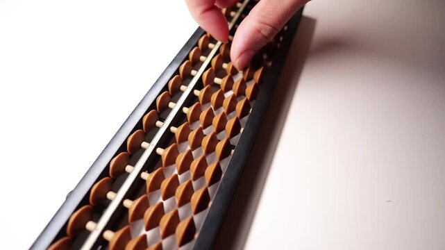 Hand using a wooden soroban abacus on white desk.