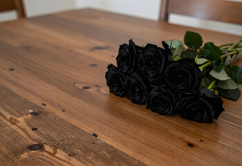 Obraz premium Grief and mourning concept bouquet of black roses on a rustic wooden table for funeral sympathy loss and sadness remembrance and memorial tribute