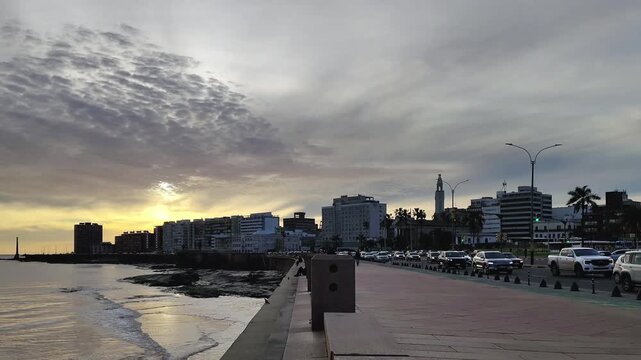 Waterfront boardwalk and busy avenue with watefront building at background over sunset cloduy sky in montevideo city, uruguay