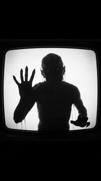 Scary monster silhouette behind old television screen with static noise and close up shot