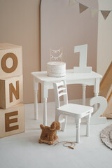Beige first birthday studio backdrop with cake on small white table, number 1 and wooden blocks © Minakryn Ruslan 