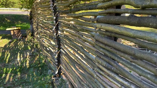 Tall rustic fence made of wooden poles, traditional rural construction in Carpathian countryside, natural barrier blending with forest and mountain landscape
