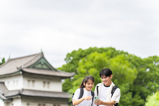 日本の観光地を旅行するアジア人観光客のカップル。インバウンド、観光、名所、スマホ、SNS、口コミ