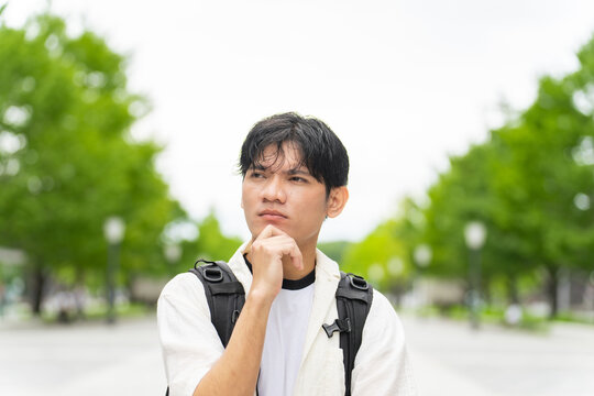 考えるアジア人男性。観光客、インバウンド、旅行、東南アジア、観光、日本、ツアー、留学生、外国人、学生