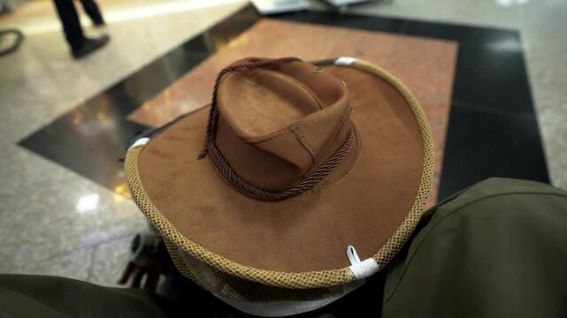 店内で茶色のサファリハットを手に取り触れてみる手元（Hand Touching Brown Safari Hat in Store）