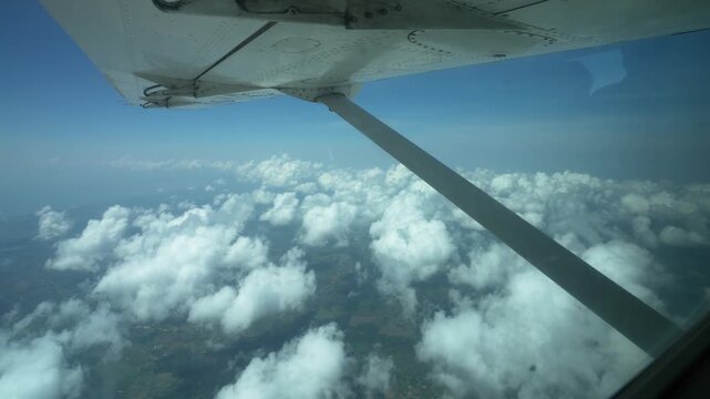 小型機の窓から見下ろす積雲と大地、上空からの眺め（Aerial View of Cumulus Clouds from Small Airplane Window）
