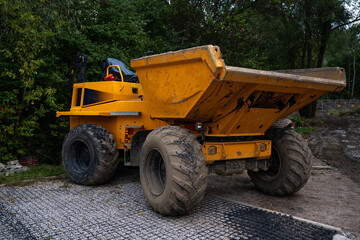 A yellow construction dump truck parked on a gravel-covered lot © Олеся Матвеева