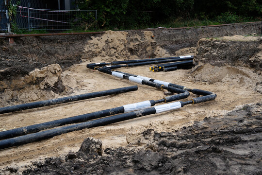 Black pipes laid in a sand-filled trench at a construction site