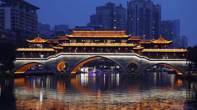View of the illuminated Anshun Bridge reflecting on the Jin River at night in Chengdu, Sichuan, China.