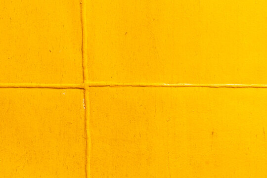 Abstract background image of yellow-painted metal plates joined by welding.