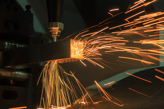 Splashing fire sparks from a laser cutting machine during a square metal tube cutting process