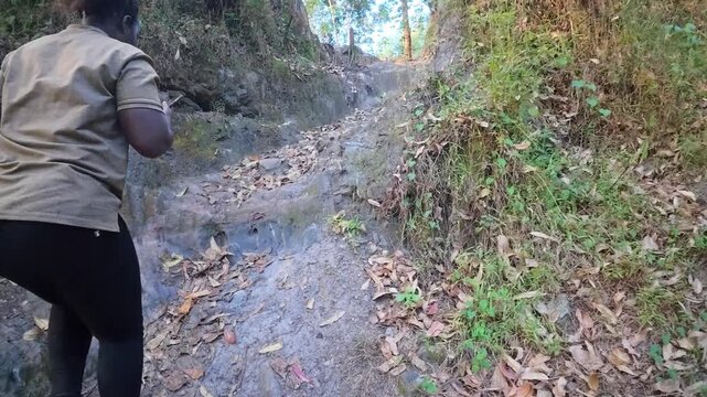ウガンダの森のトレイルを登るハイカー、落ち葉に覆われた急な山道（Hiker Climbing Forest Trail in Uganda）