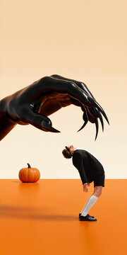 Stylish young man bends beneath enormous clawed hands in minimal orange studio with playful fear. Fashion editorial, beautiful weirdness, Halloween ads concept